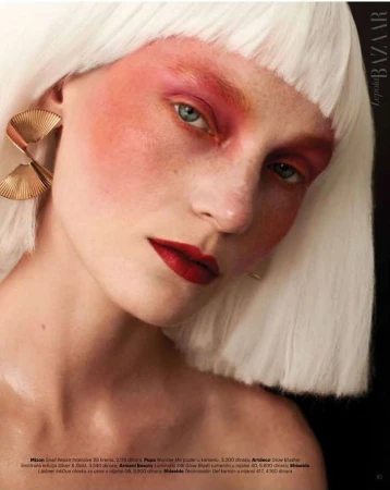 Close-up portrait of a woman with white bob wig, bold pink eyeshadow, deep red lips, and large pleated gold earrings by Alena Sazonova