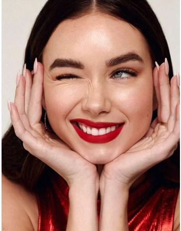 Close-up portrait of a woman winking with bright red lipstick and hands framing her face