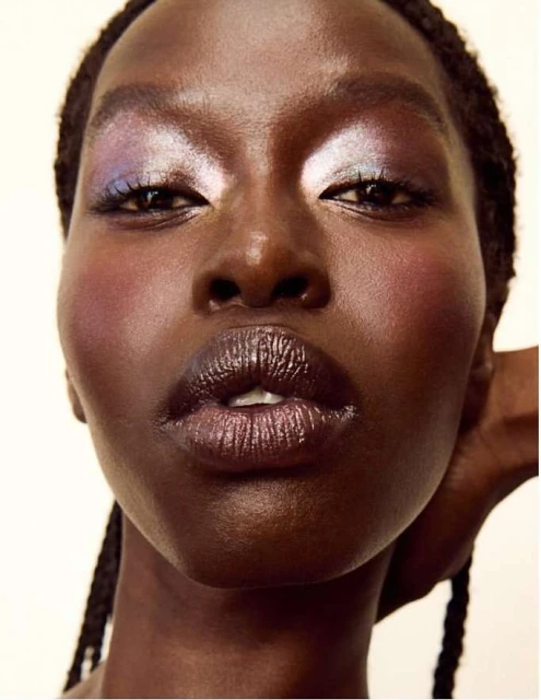 Close-up portrait of an African-American woman with iridescent eyeshadow and dark lipstick in a beauty and fashion style makeup shot.