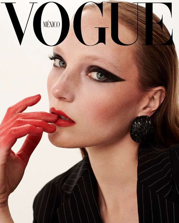 Vogue Mexico cover featuring a model with red lipstick and painted hand, wearing a pinstripe blazer and large black beaded earring.