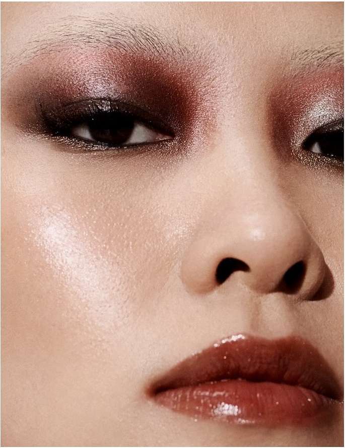 Close-up of a woman's face with dramatic, shimmering brown eyeshadow and glossy lips, highlighting beauty and makeup artistry.