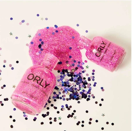 Two bottles of pink Orly nail polish surrounded by scattered purple and pink confetti, displayed on a white surface.