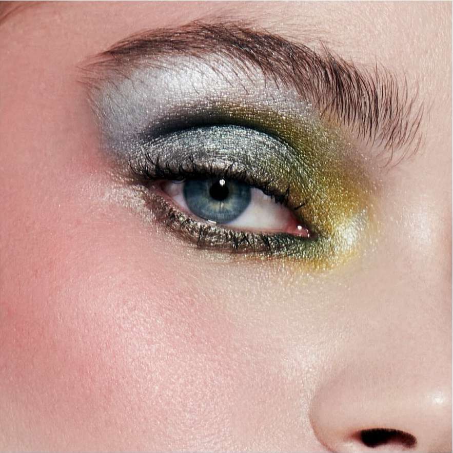 Close-up macro shot of a blue eye with metallic silver and gold eyeshadow and dark eyelashes by photographer Alena Sazonova