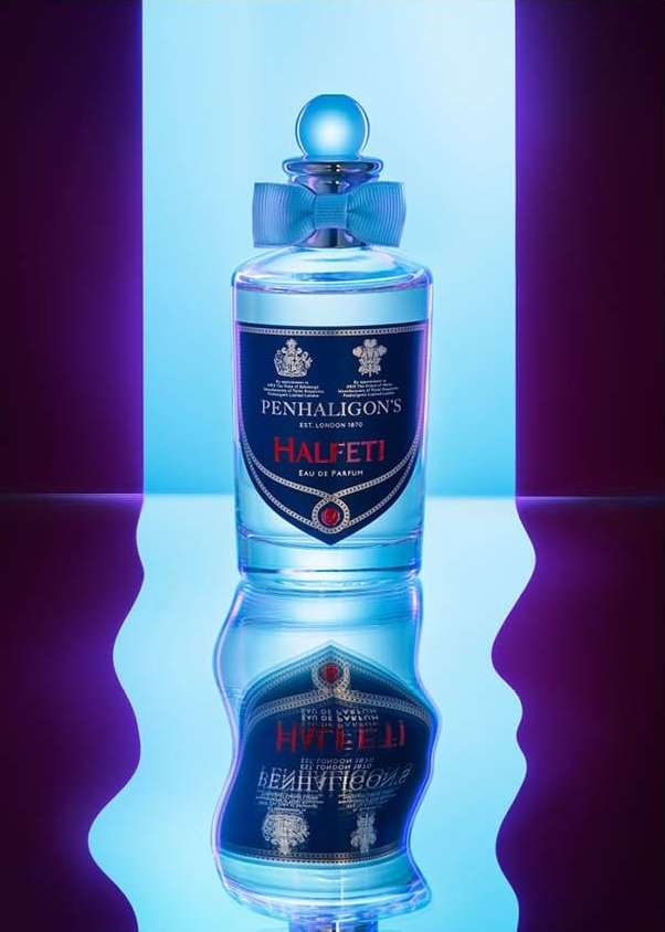 Elegant studio shot of a Penhaligon's Halfeti Eau de Parfum bottle with a blue ribbon, against a vibrant blue and purple backdrop.