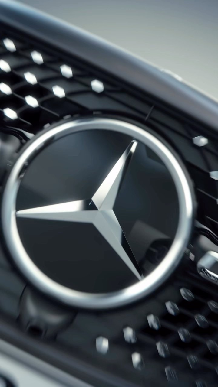 Close-up shot of a Mercedes-Benz logo on the front grille of a car, featuring a silver emblem against a black background.