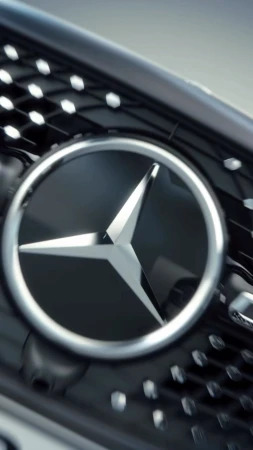 Close-up shot of a Mercedes-Benz logo on the front grille of a car, featuring a silver emblem against a black background.