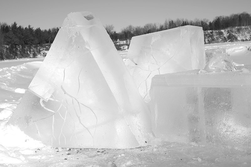 Icy landscape featuring geometric ice blocks in an outdoor setting with snow-covered ground and a background of trees and sky.