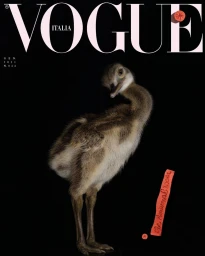 A young ostrich chick stands centrally against a solid black background below prominent VOGUE ITALIA magazine masthead lettering.