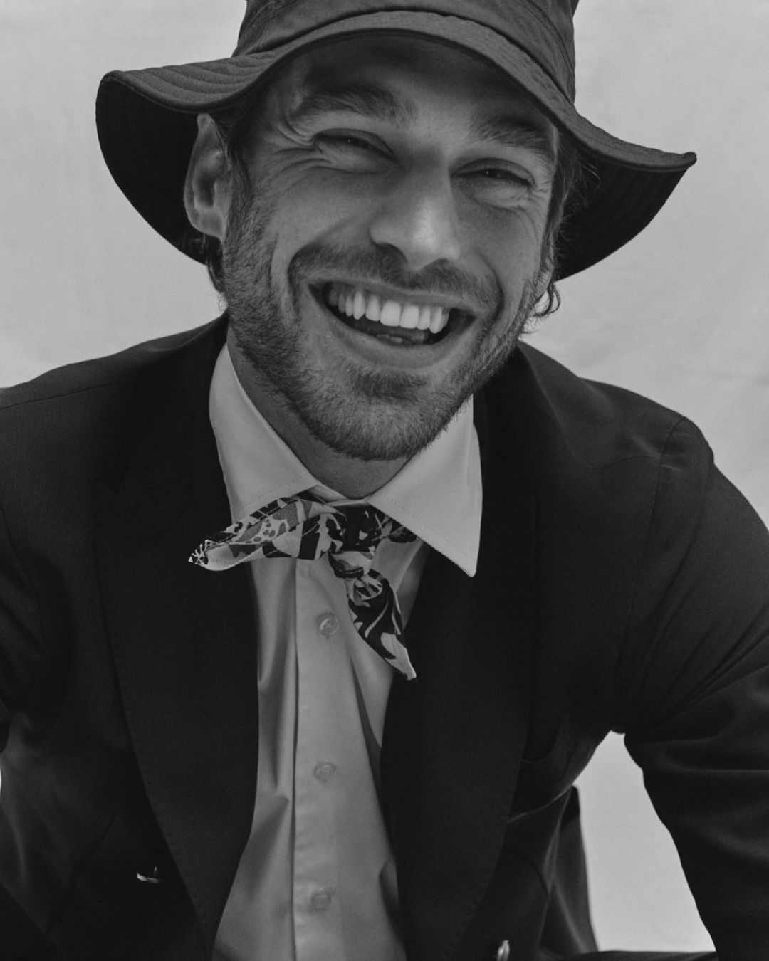 Smiling man in bucket hat and suit with patterned neckscarf photographed by Alessandro Burzigotti in Milan