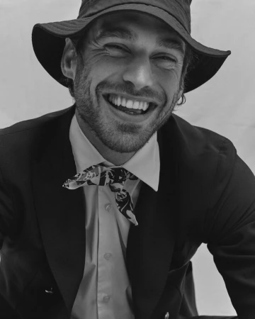 Smiling man in bucket hat and suit with patterned neckscarf photographed by Alessandro Burzigotti in Milan