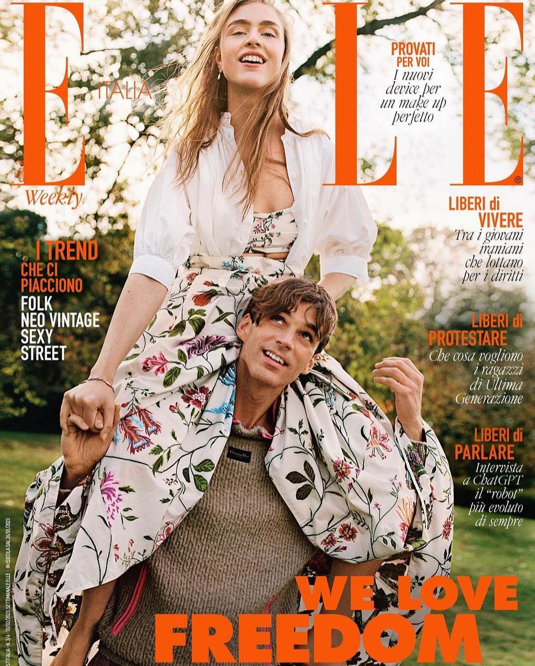Elle Italia magazine cover featuring a woman riding on a man's shoulders in an outdoor setting with a floral pattern.