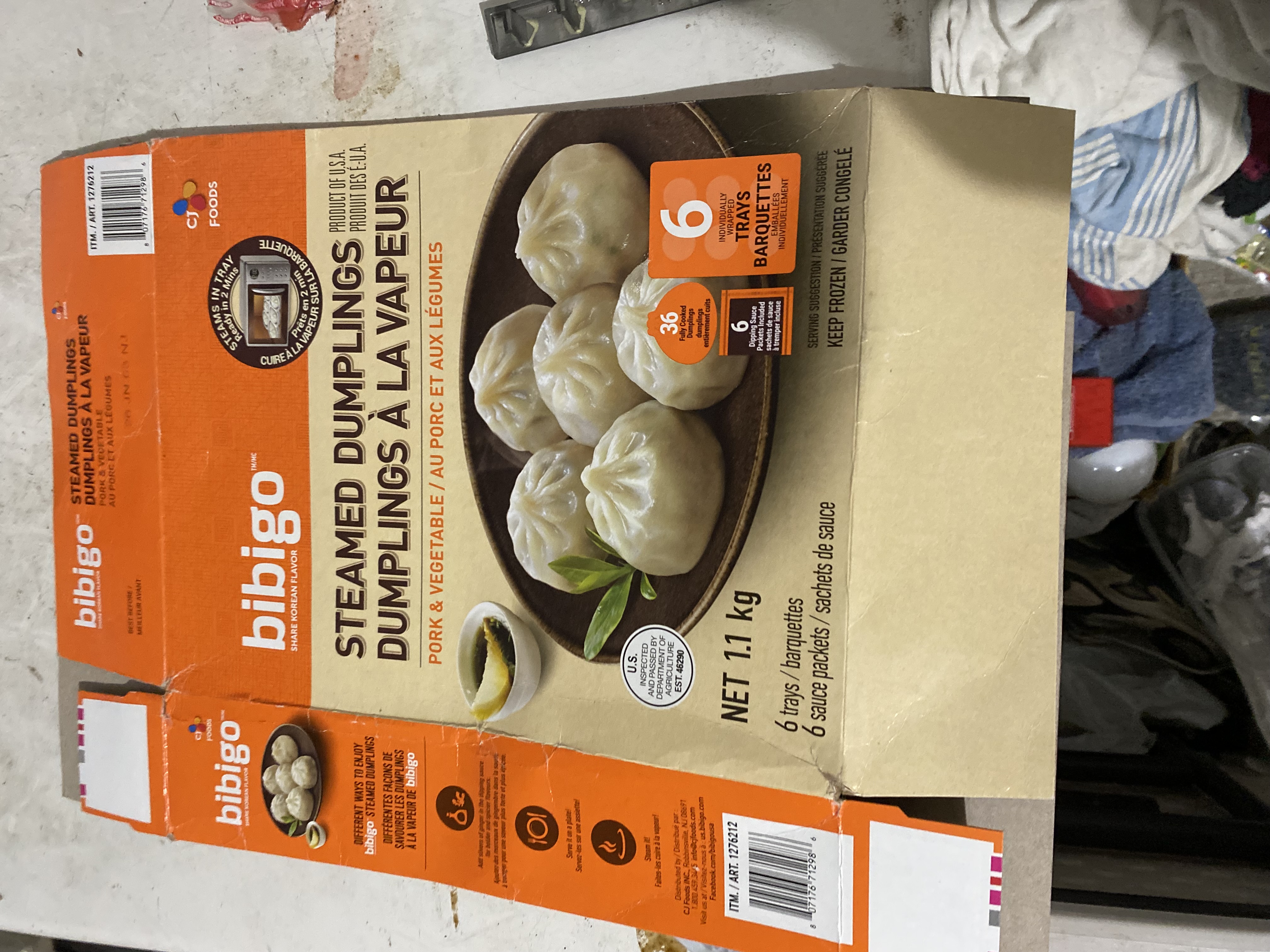 Box of Bibigo steamed dumplings with pork and vegetable filling. Korean-style dumplings in packaging on an indoor setting.