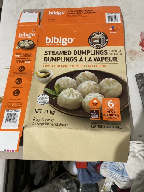 Box of Bibigo steamed dumplings with pork and vegetable filling. Korean-style dumplings in packaging on an indoor setting.