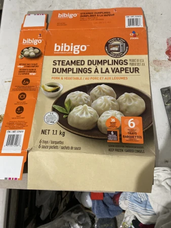 Box of Bibigo steamed dumplings with pork and vegetable filling. Korean-style dumplings in packaging on an indoor setting.
