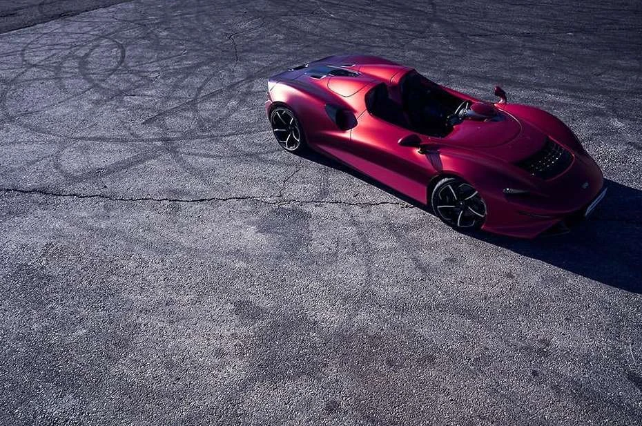 Sleek, red sports car parked on asphalt with visible tire tracks, captured in an eye-level, outdoor shot highlighting automotive design and performance.