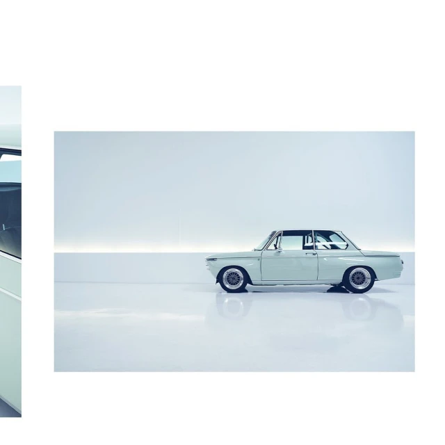 Light-blue vintage coupe automobile parked indoors, side profile, with white wall and floor background, automotive photography.