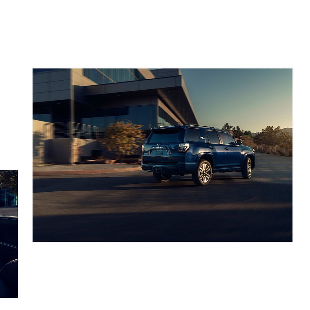 Blue SUV driving on a paved road with a modern building in the background, showcasing automotive design and outdoor driving.