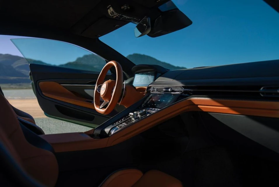 Interior view of a car with brown leather seats, a steering wheel, and a dashboard against a desert background on a sunny day.