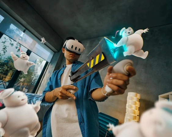 Person using VR headset with a virtual reality gaming gun, surrounded by animated marshmallows in a modern interior setting. 