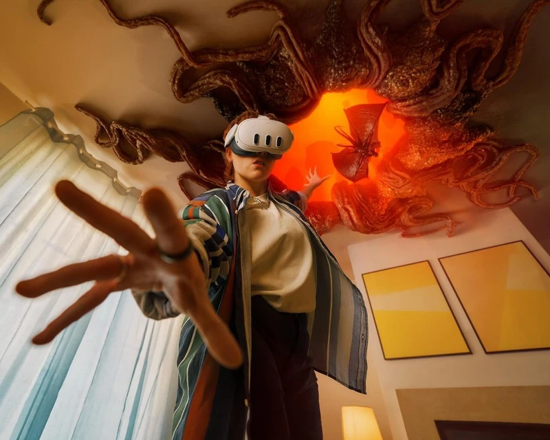 Woman wearing a VR headset reaches toward the camera; a digitally-rendered portal with tentacles is visible on the ceiling above.