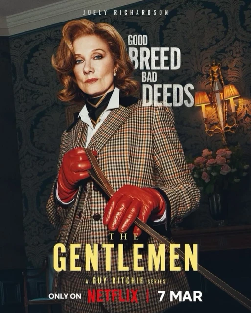 Joely Richardson stars in 'The Gentlemen' wearing a plaid suit and red gloves, holding a riding crop, in a promotional shot.