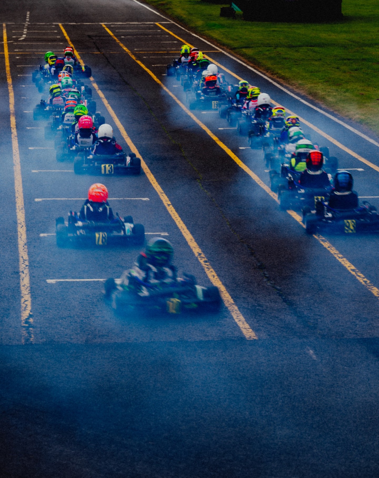 Go-kart racing on a track with a line of racers speeding towards the finish line in a high-speed competition.