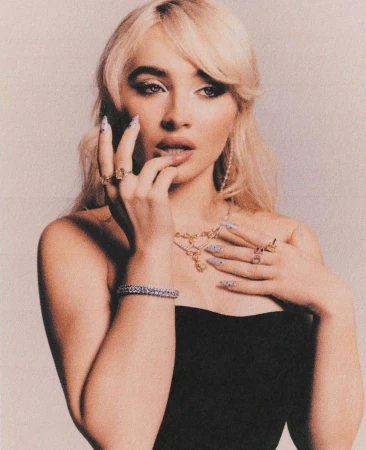 Portrait of blonde woman in black top wearing rings and necklace, photographed by Alex Harper.