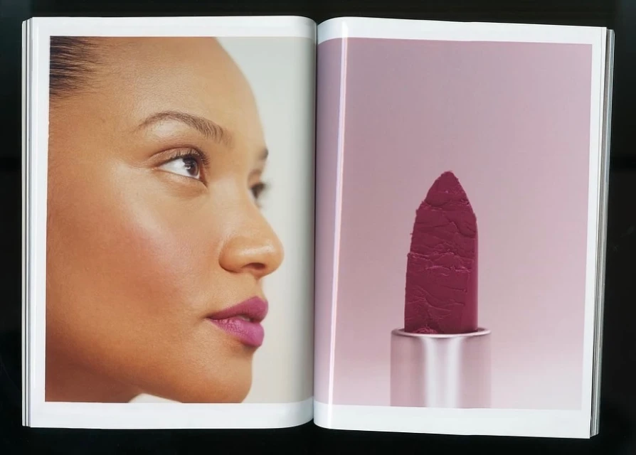 Close-up of a woman's face alongside a lipstick tube in a magazine ad, showcasing makeup and beauty.