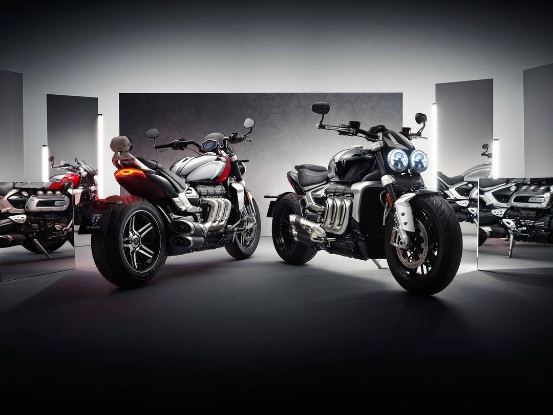 Motorcycles aligned for a studio shot featuring sleek design and reflective surfaces, highlighting automotive craftsmanship in a staged setting.
