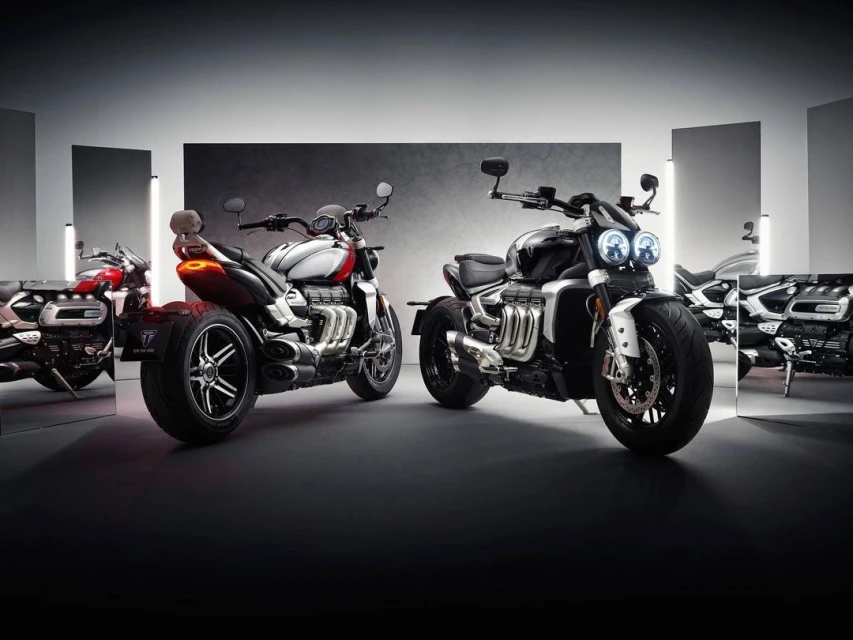 Motorcycles aligned for a studio shot featuring sleek design and reflective surfaces, highlighting automotive craftsmanship in a staged setting.