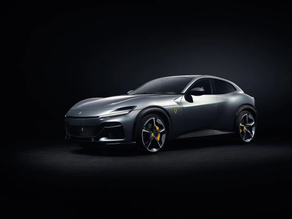 Sleek silver Ferrari Purosangue SUV showcased against a black backdrop, highlighting its sporty design, wheels, and emblem.