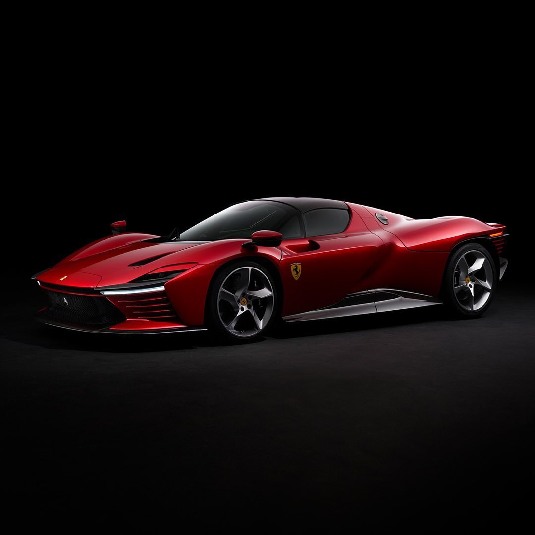 A luxurious red Ferrari sports car is showcased against a sleek black backdrop, highlighting its aerodynamic design and high-performance features.