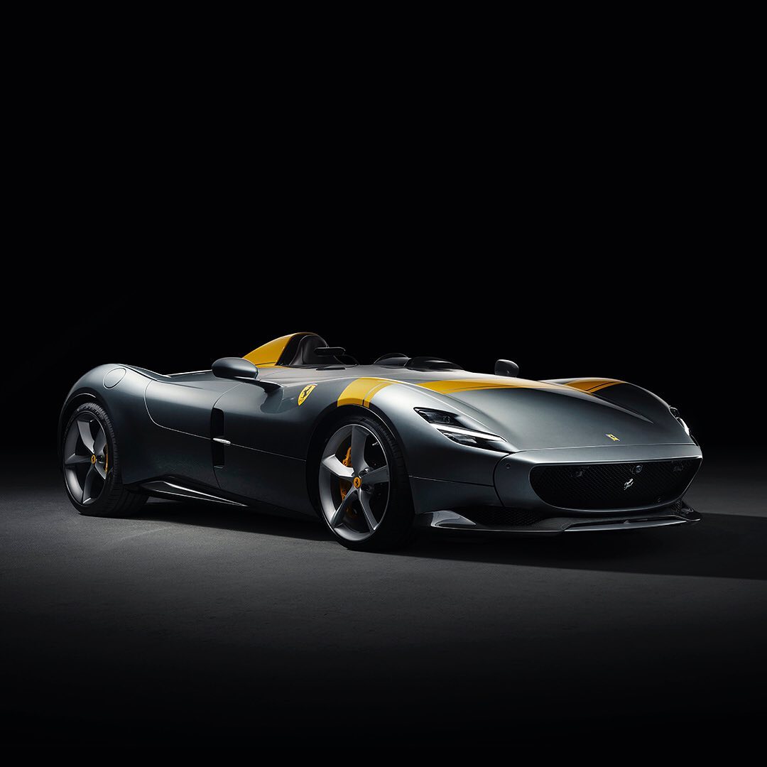 Gray and yellow Ferrari Monza SP1 sports car. Car features aerodynamic design, sleek lines, no windshield and seating for one.