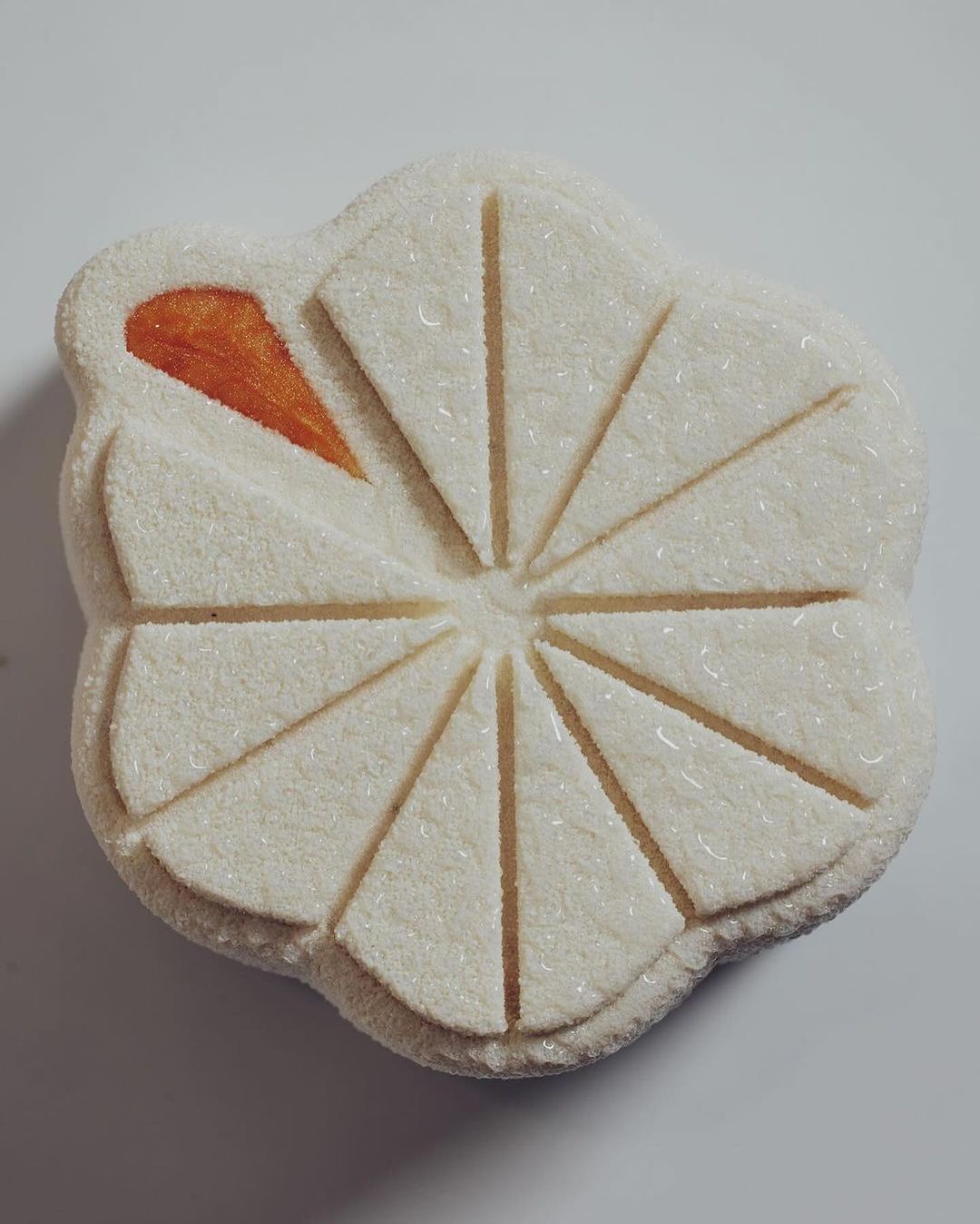 Close-up of a flower-shaped Japanese wagashi confectionery with white and orange hues, displaying delicate craftsmanship and detail.