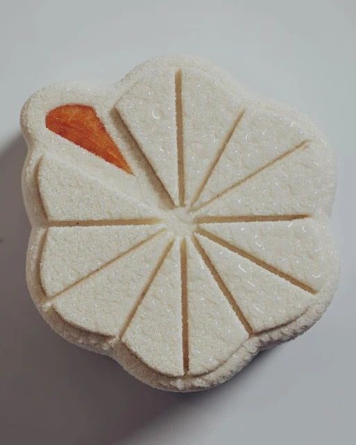 Close-up of a flower-shaped Japanese wagashi confectionery with white and orange hues, displaying delicate craftsmanship and detail.