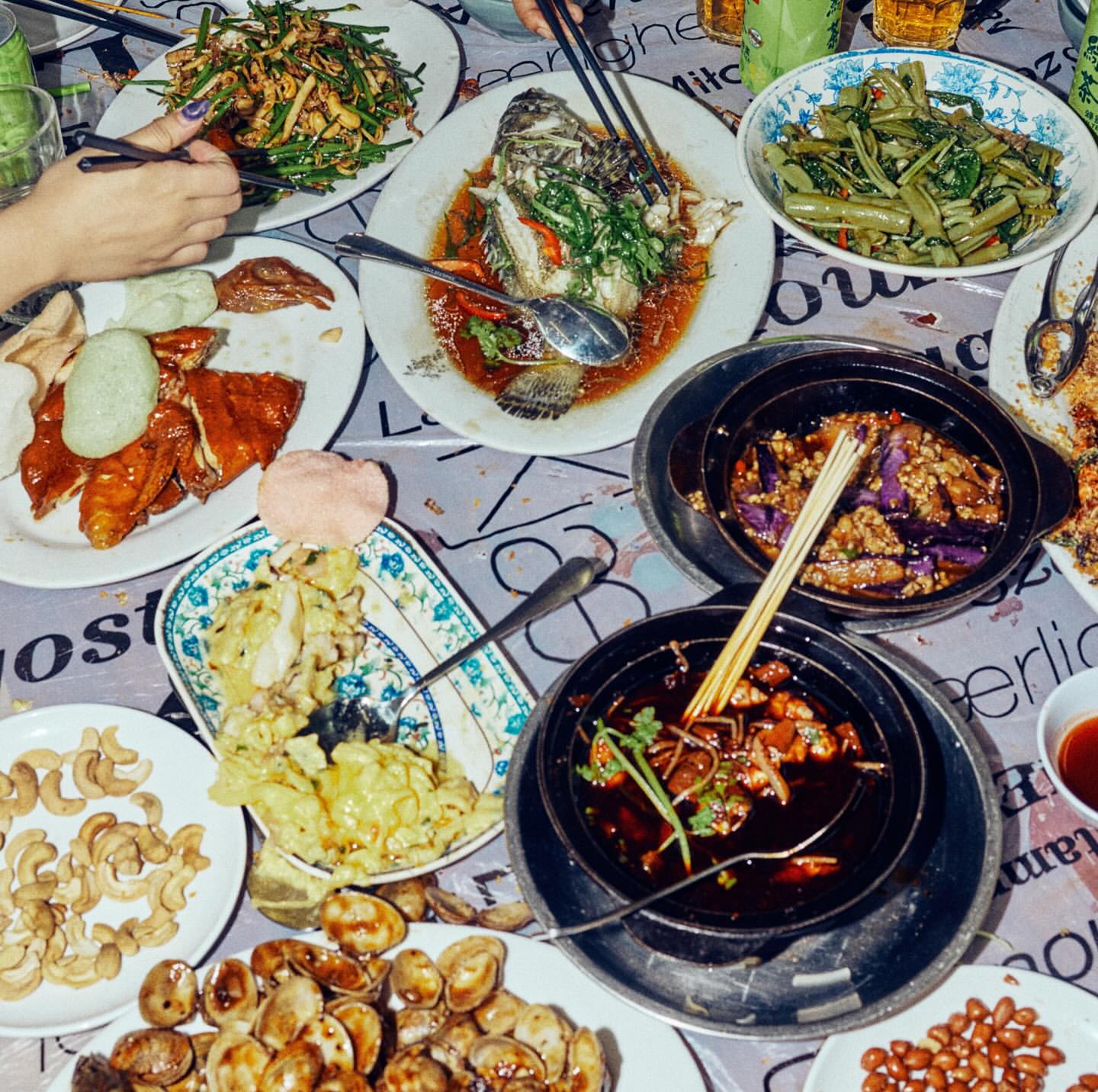 Overhead shot of a table laden with an array of vibrant Chinese dishes, including fish, vegetables, and meats, creating a rich, diverse culinary display.