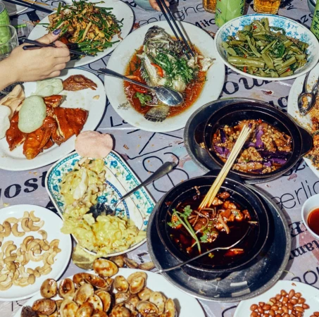 Overhead shot of a table laden with an array of vibrant Chinese dishes, including fish, vegetables, and meats, creating a rich, diverse culinary display.