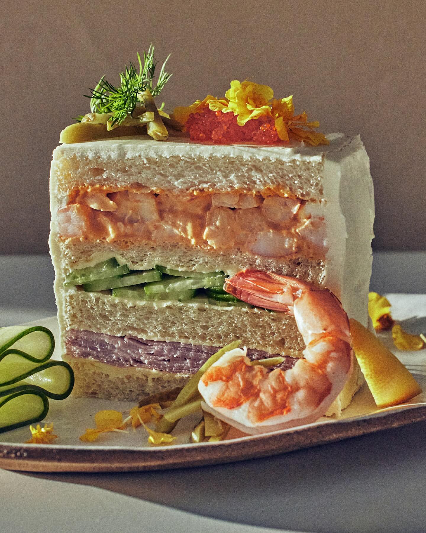 A culinary creation: a multi-layered sandwich with shrimp, cucumber, and ham, presented on a decorative plate, a gastronomic work of art.