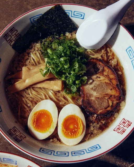 Overhead shot of a bowl of ramen featuring noodles, broth, pork, seaweed, scallions, soft boiled eggs, and bamboo shoots.