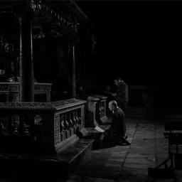 Two men kneeling and standing inside a dark ornate interior space, captured in dramatic low-key monochrome by Alex Majoli.
