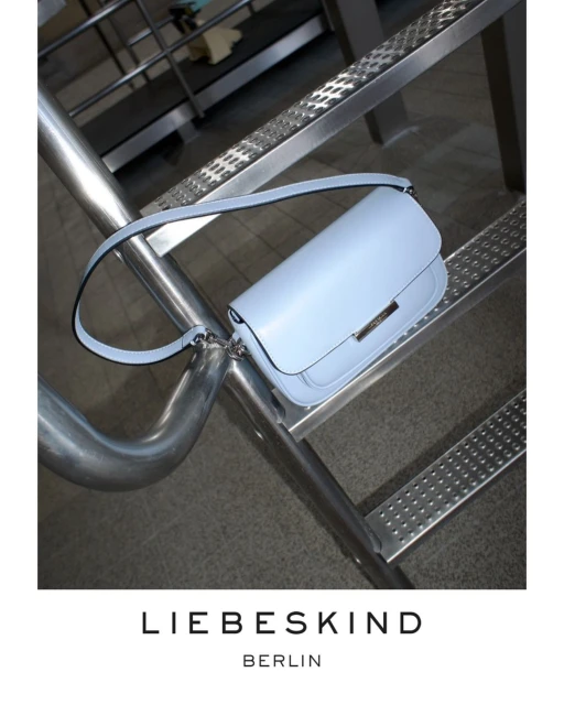 Light blue Liebeskind handbag on a metal grate background, showcasing the brand's design and construction details.