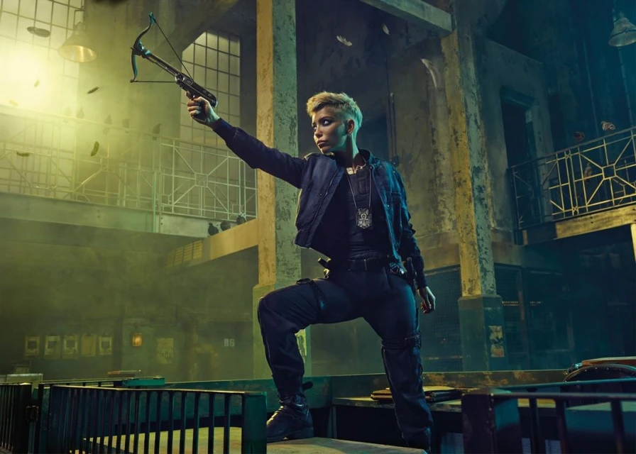 A confident woman stands on a rooftop with a crossbow in hand, dressed in dark attire, set against an urban backdrop with moody lighting.