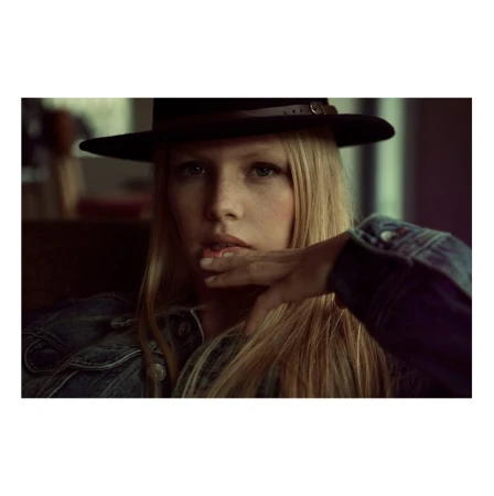 Portrait of a blonde woman wearing a dark fedora and a denim jacket by photographer Alexa Singer.