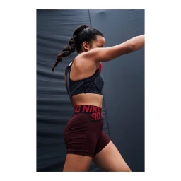Woman in activewear throwing a punch against a dark grey backdrop