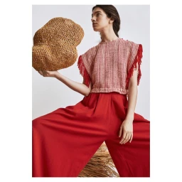 Woman in red fringed top and trousers holding a large woven straw bag by photographer Alexander Neumann
