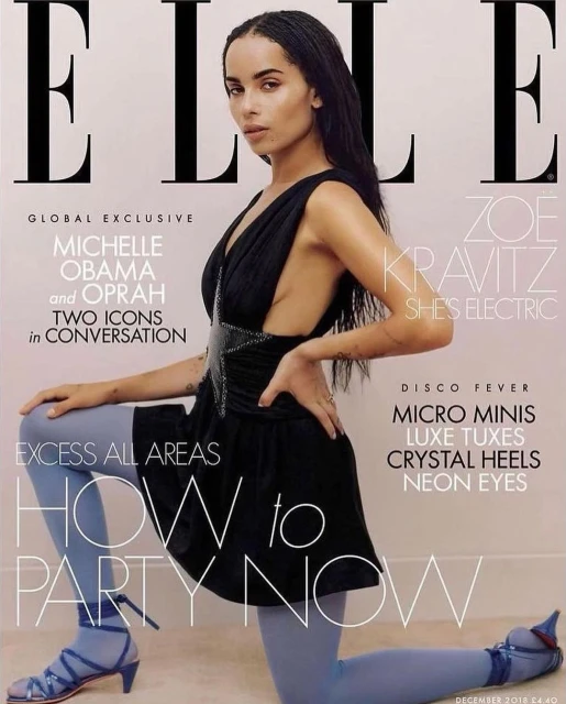 Zoe Kravitz on the cover of Elle magazine, December 2018 issue, wearing a black dress and blue tights, kneeling against a neutral backdrop.