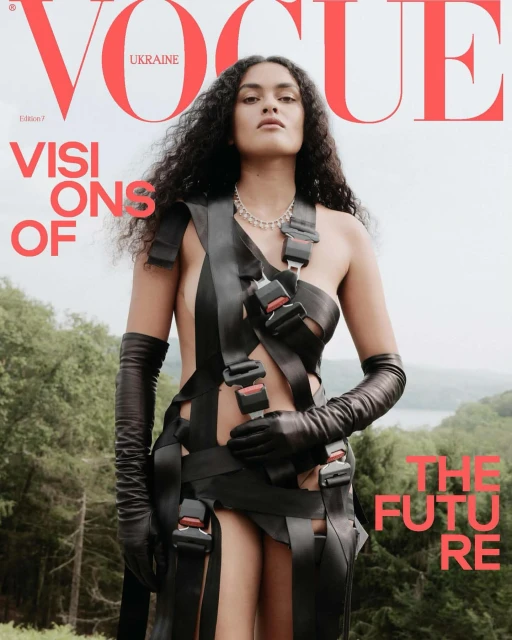 Vogue Ukraine cover featuring a young woman with dark curly hair wearing seatbelt fashion, gloves, and a necklace, posing outdoors.
