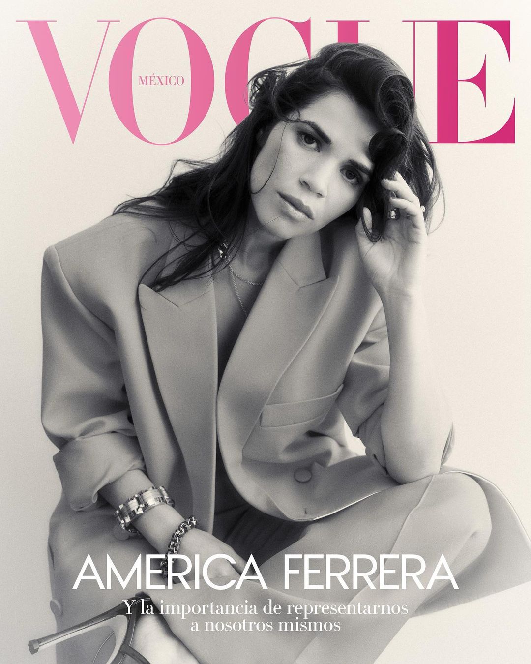 Vogue Mexico cover featuring America Ferrera in a tan blazer, bracelets, and peep-toe heels, posing in front of a light-pink logo background.