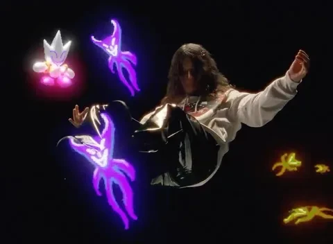 Woman in a sweatshirt poses in a surreal digital composition featuring glowing cartoon creatures on a dark background in a studio setting.