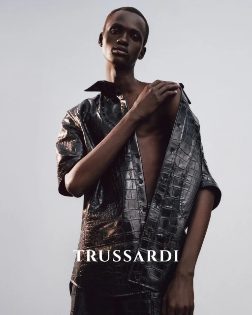 Fashion editorial shot of an African American male model wearing a crocodile-patterned shirt, posing against a gradient background.